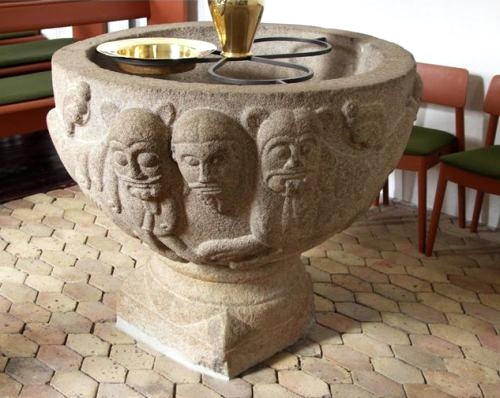 Romanesque font with confronting lions around a man's head in Stenild Church
